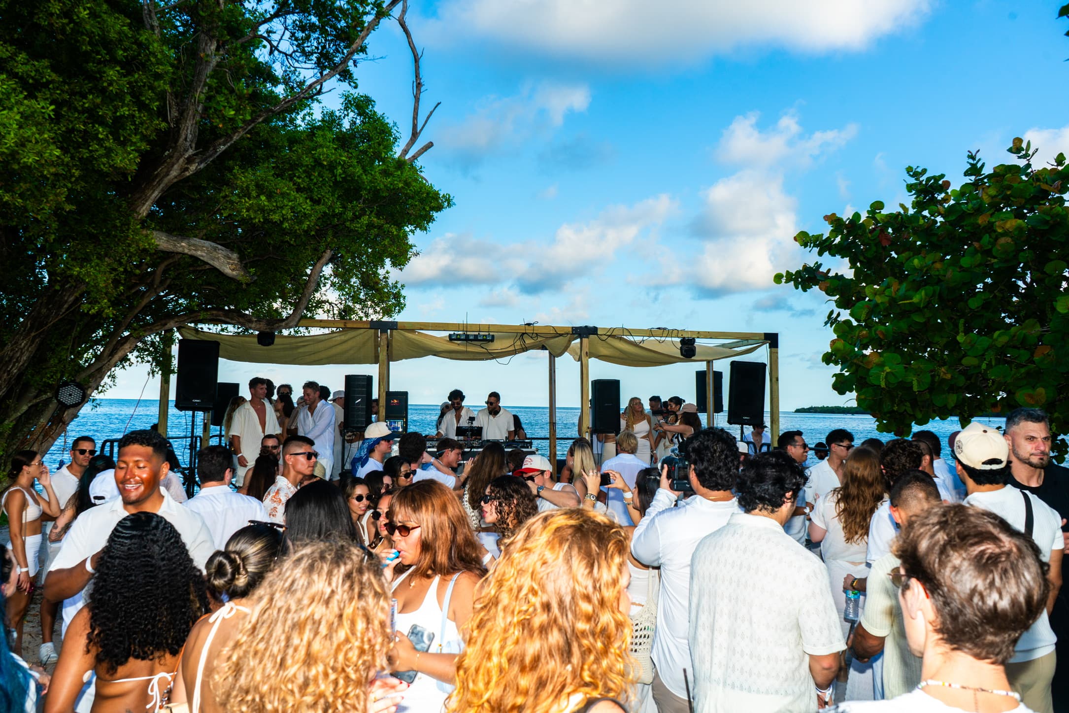 DJ performing for a beach party crowd at a First Reef event
