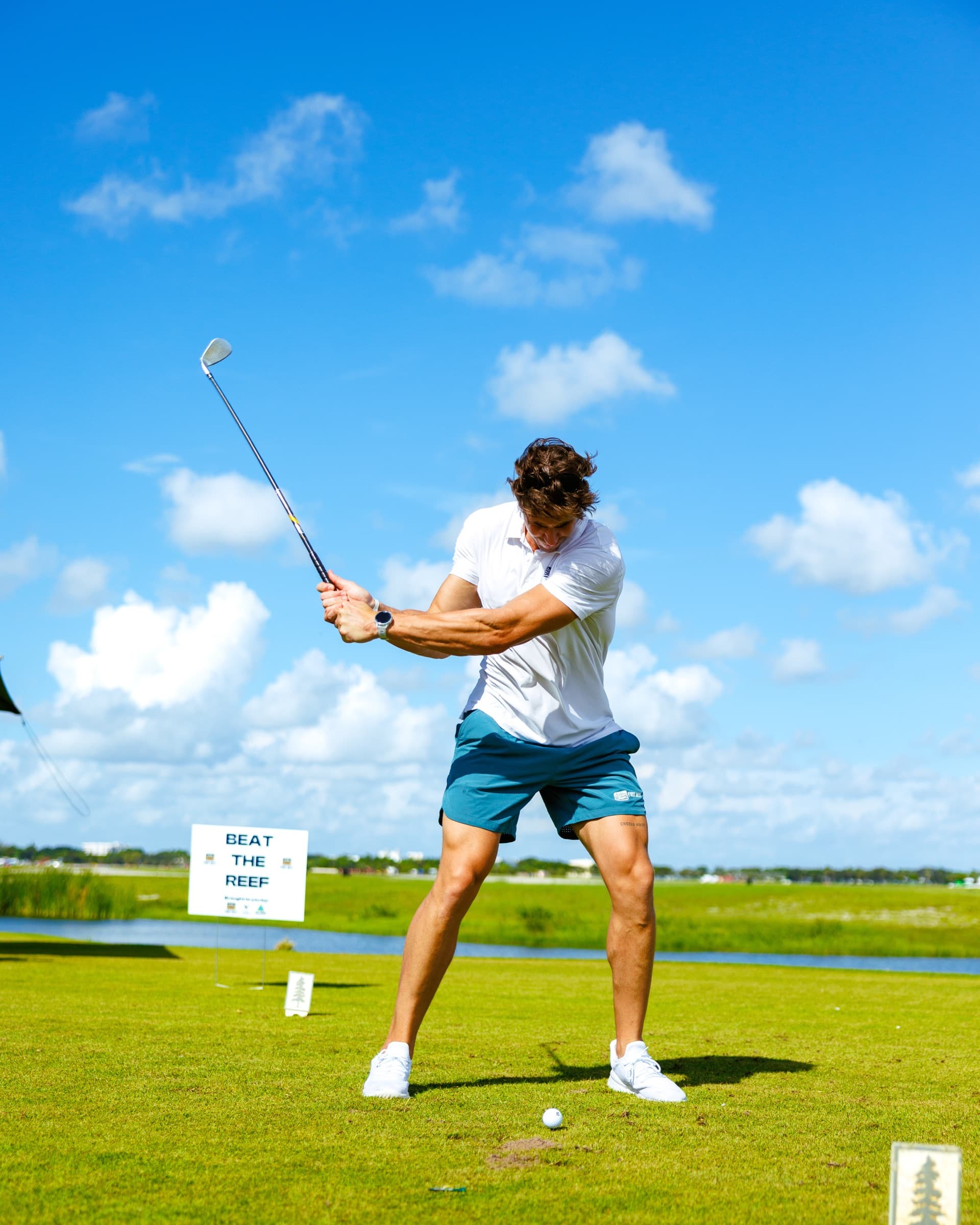 Golfer mid-swing at a First Reef wellness event